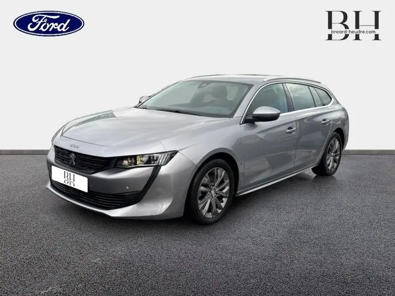 Peugeot 508 SW gris Platinium vue 3/4 avant droit, mettant en valeur sa calandre noire et ses jantes alu.