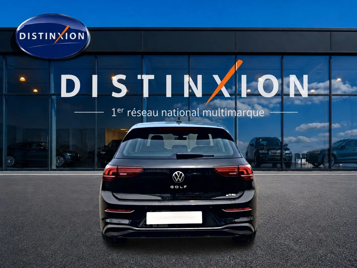 Vue arrière d'une Volkswagen Golf noire 2026 garée devant une vitrine avec logo Distinxion visible en arrière-plan.