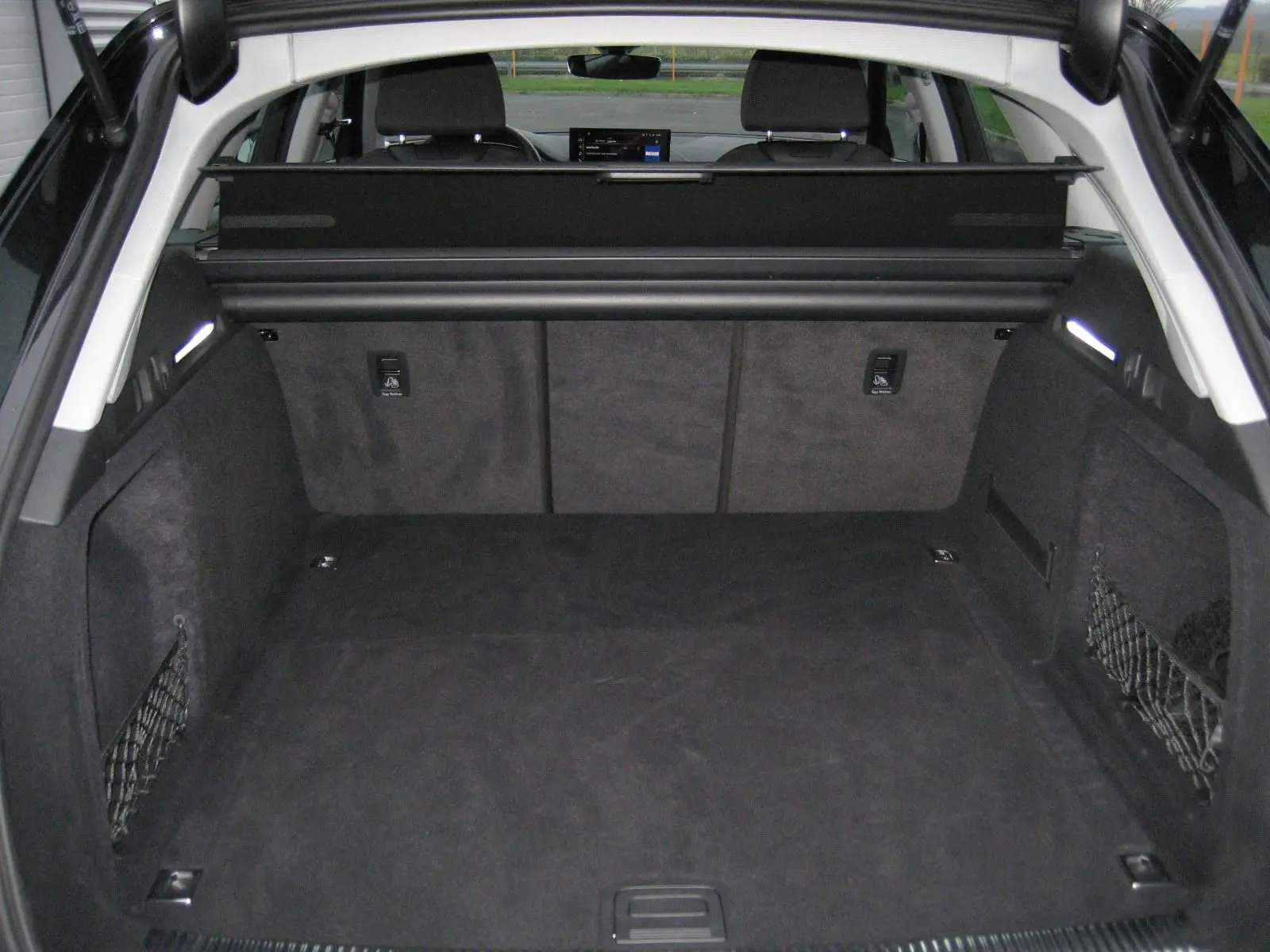 Coffre spacieux noir de l'Audi A4 Avant 3.5 TDI 2022 vu de l'arrière avec filet de rangement sur les côtés.