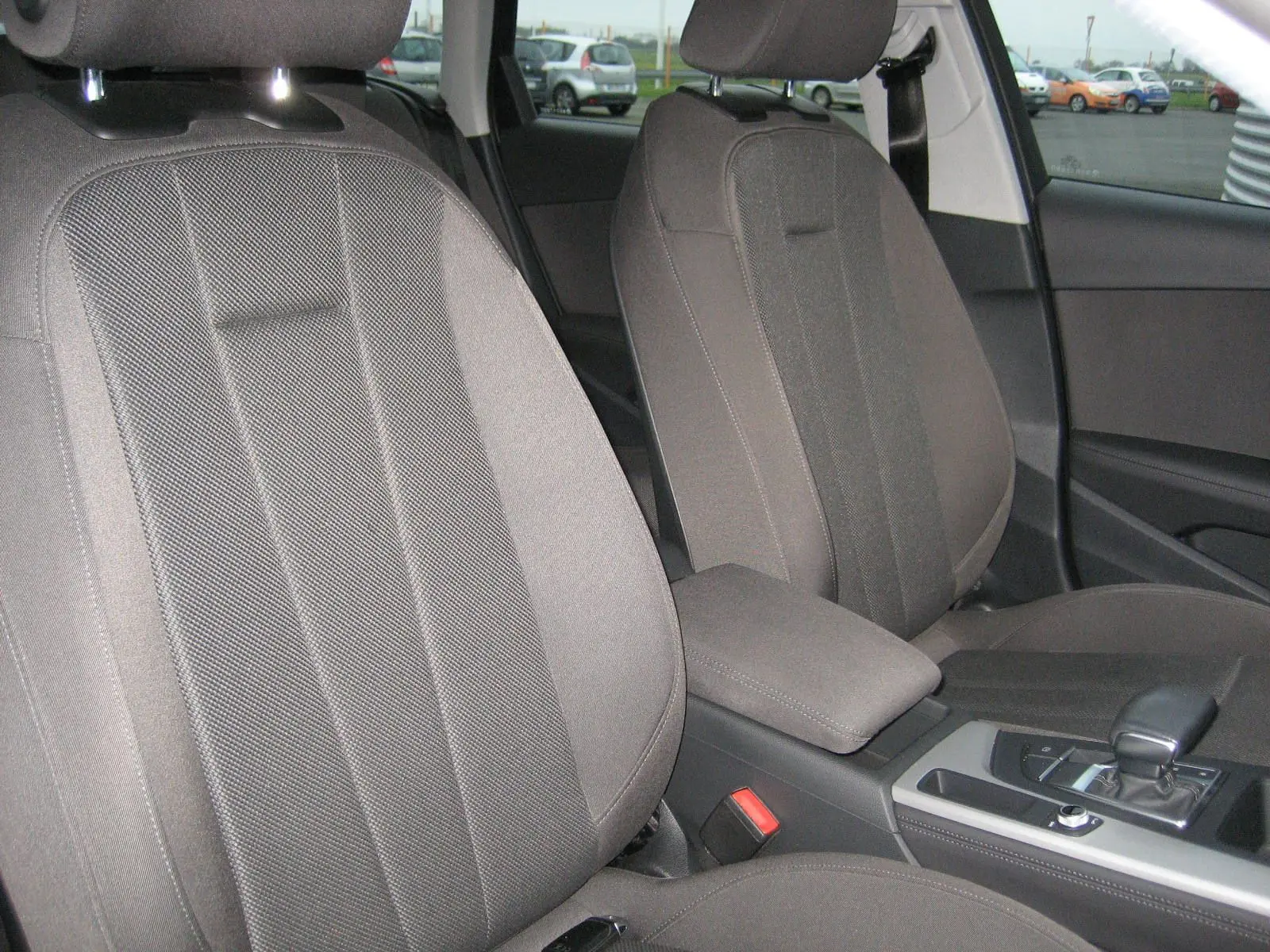 Vue rapprochée des sièges avant gris et de la console centrale d'une Audi A4 Avant noire de 2022 avec boîte automatique.