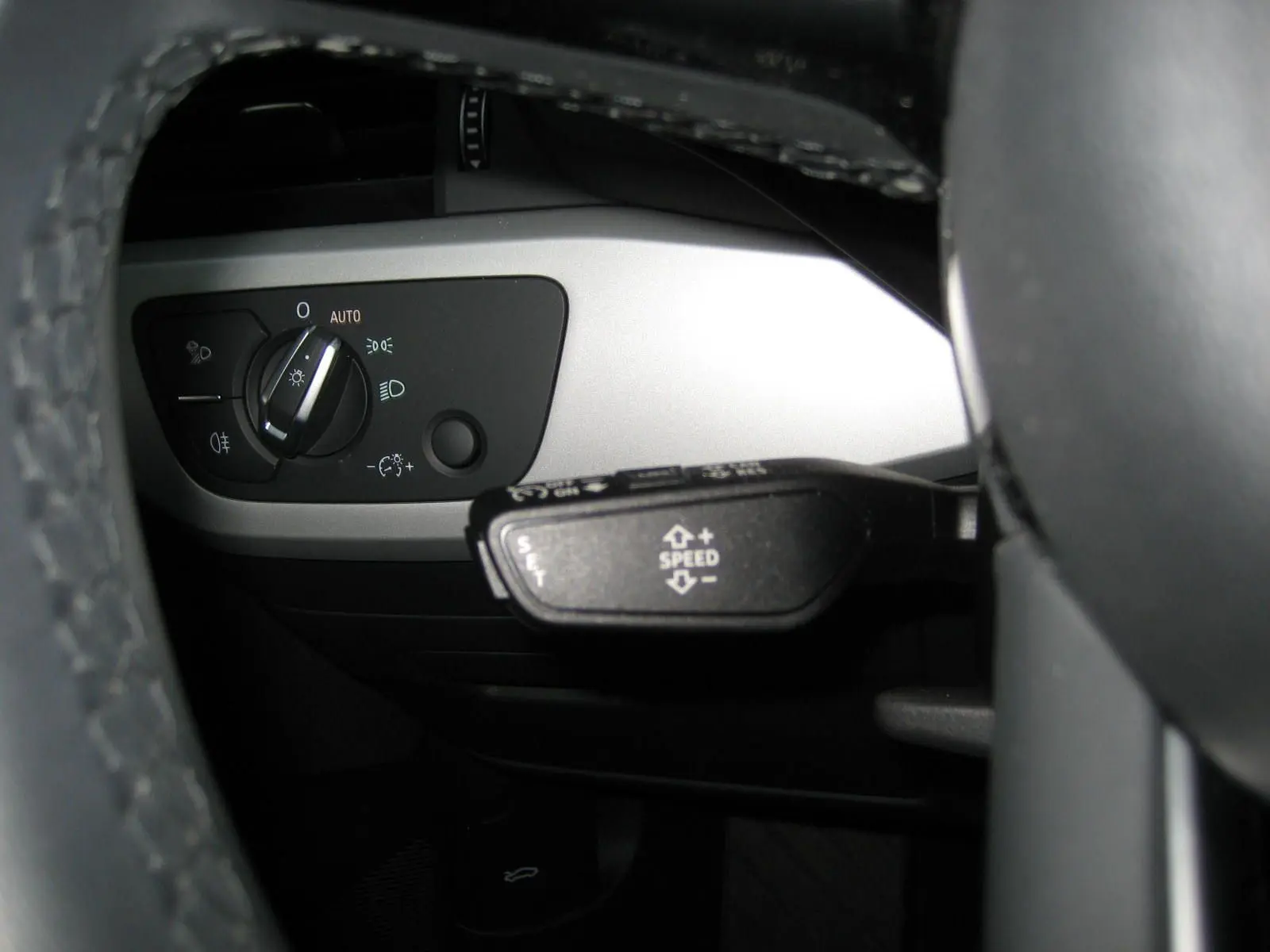 Gros plan sur le commodo de régulateur de vitesse et le sélecteur d'éclairage côté gauche du tableau de bord d'une Audi A4 Avant noire.