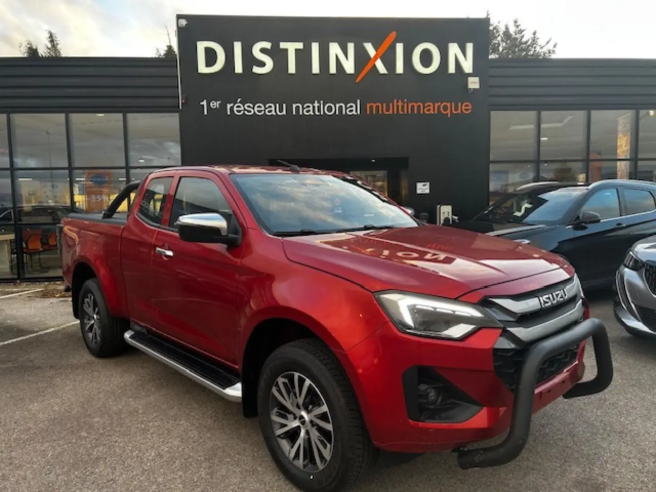 Vue 3/4 avant gauche du pick-up Isuzu D-MAX rouge métallisé avec bullbar noir et jantes alliage bicolores