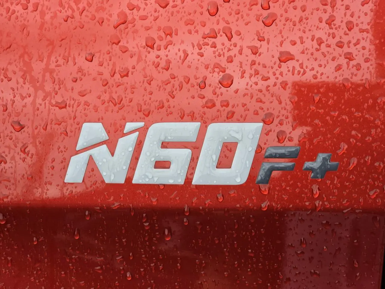 Gros plan sur l’inscription N60 F+ sur la carrosserie orange métallisée d’un Isuzu D-MAX III NEW 2025.