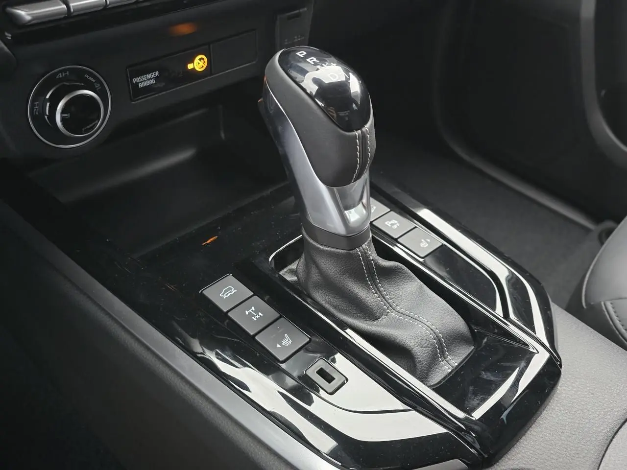 Gros plan sur le levier de vitesse automatique noir et chrome de l'Isuzu D-MAX III NEW 2025 avec commandes 4x4 et sièges cuir.