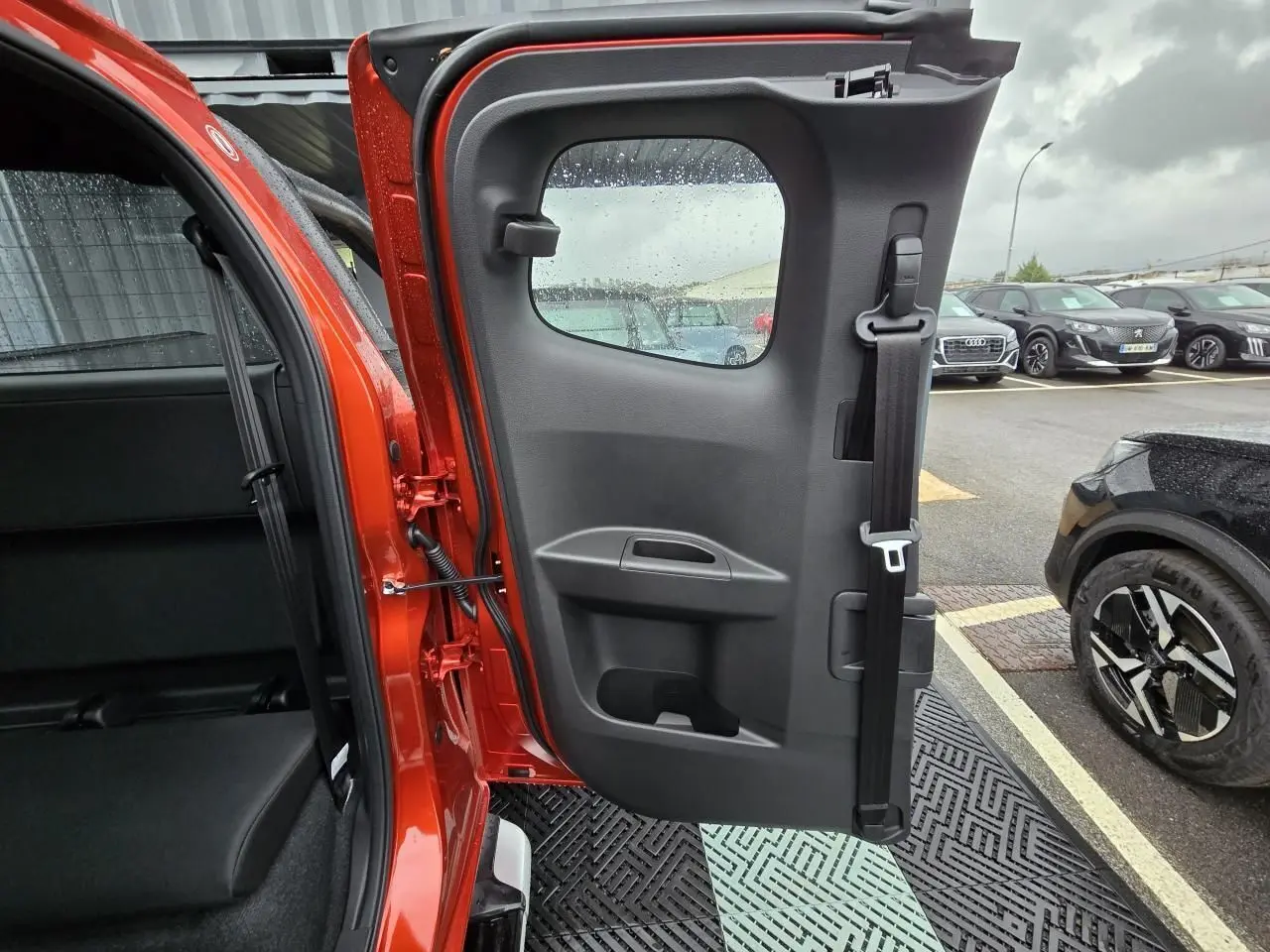 Vue intérieure de la porte arrière droite orange métallisée d'un Isuzu D-MAX III NEW 2025 avec ceinture de sécurité intégrée.