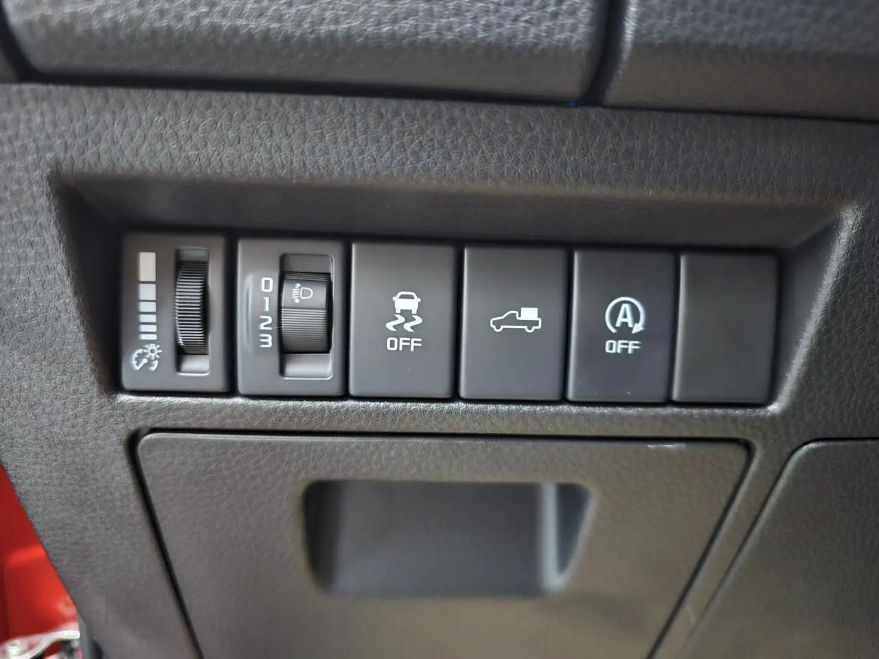 Panneau de commandes intérieures avec réglage luminosité, contrôle phares et aides à la conduite sur Isuzu D-MAX orange.