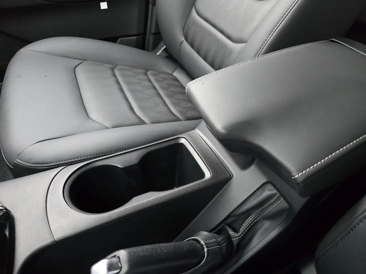 Gros plan sur la console centrale noire et le siège conducteur en cuir gris du pick-up Isuzu D-MAX III NEW 2025.