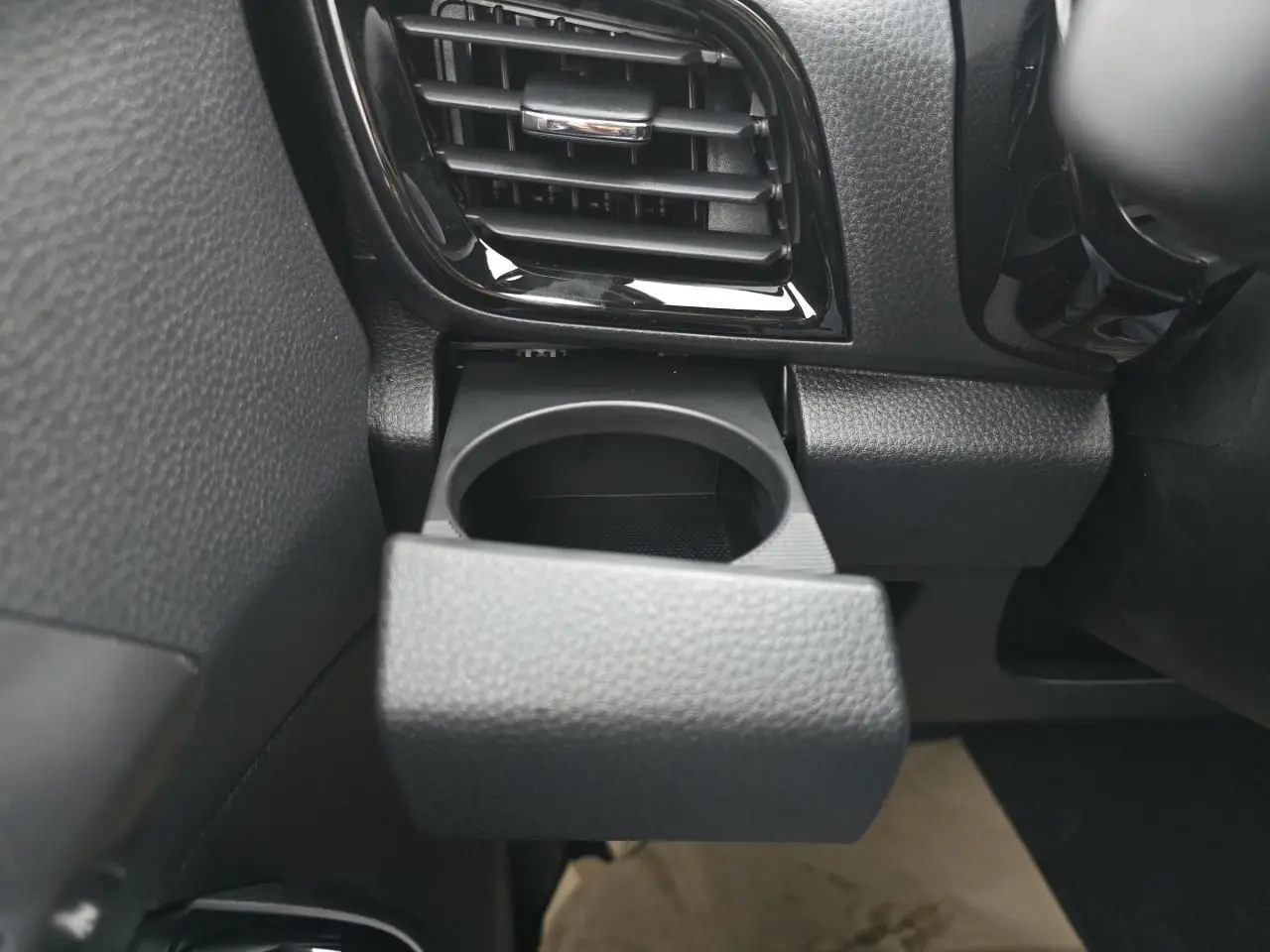 Gros plan sur le porte-gobelet noir déployé à gauche du tableau de bord du pick-up Isuzu D-MAX 2025.