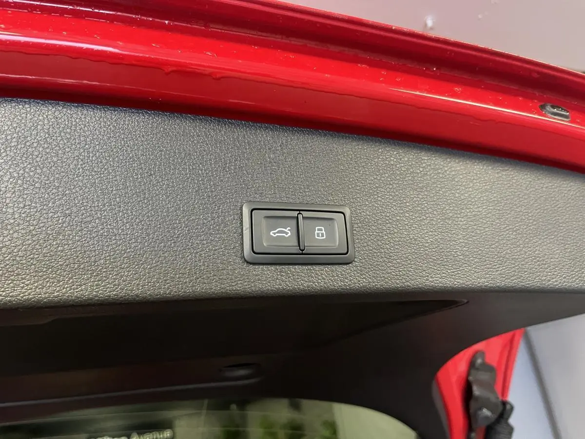 Boutons d'ouverture et de verrouillage du hayon électrique sur la partie intérieure rouge du coffre d'un Audi Q2 rouge S line 2024