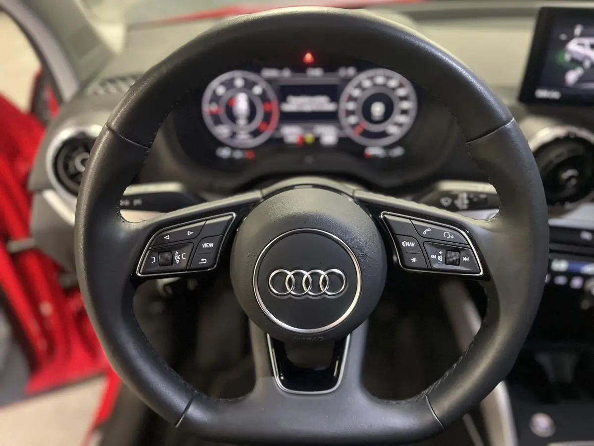 Volant sport en cuir multifonction de l'Audi Q2 rouge 2024, vue rapprochée du poste de conduite