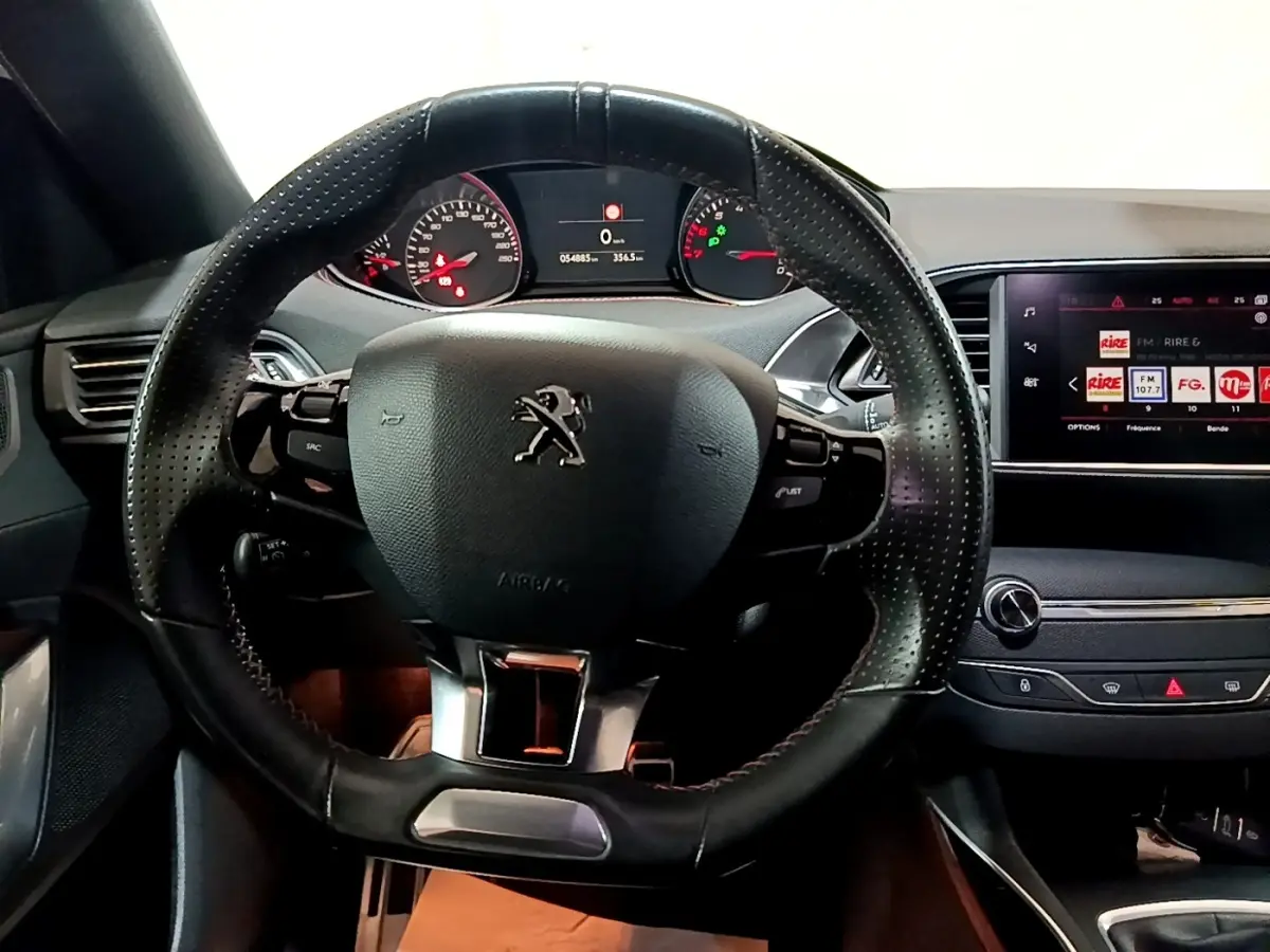 Vue intérieure centrée sur le volant cuir perforé et le tableau de bord numérique de la Peugeot 308 GT Line 2019.