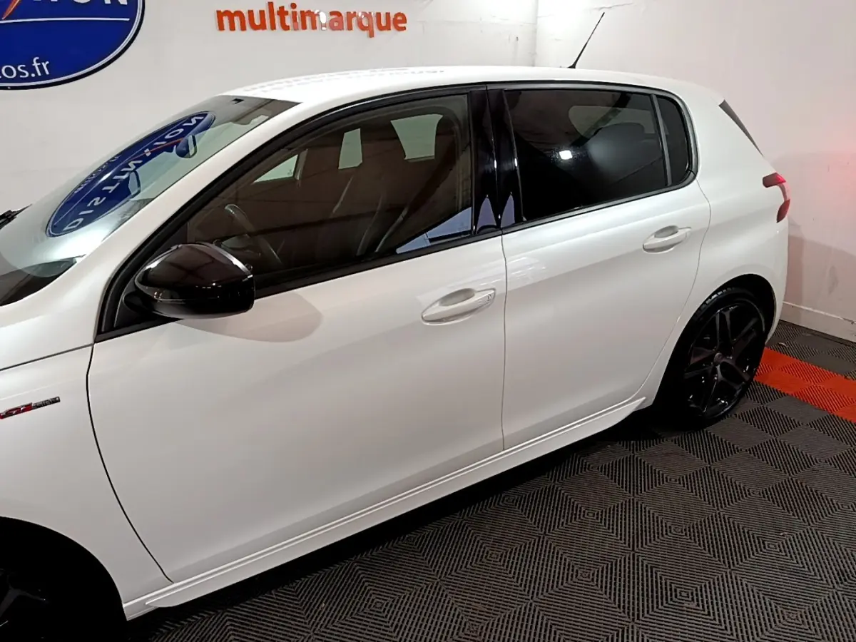 Profil côté gauche d'une Peugeot 308 GT Line blanche avec rétroviseurs noirs et jantes alliage foncé.