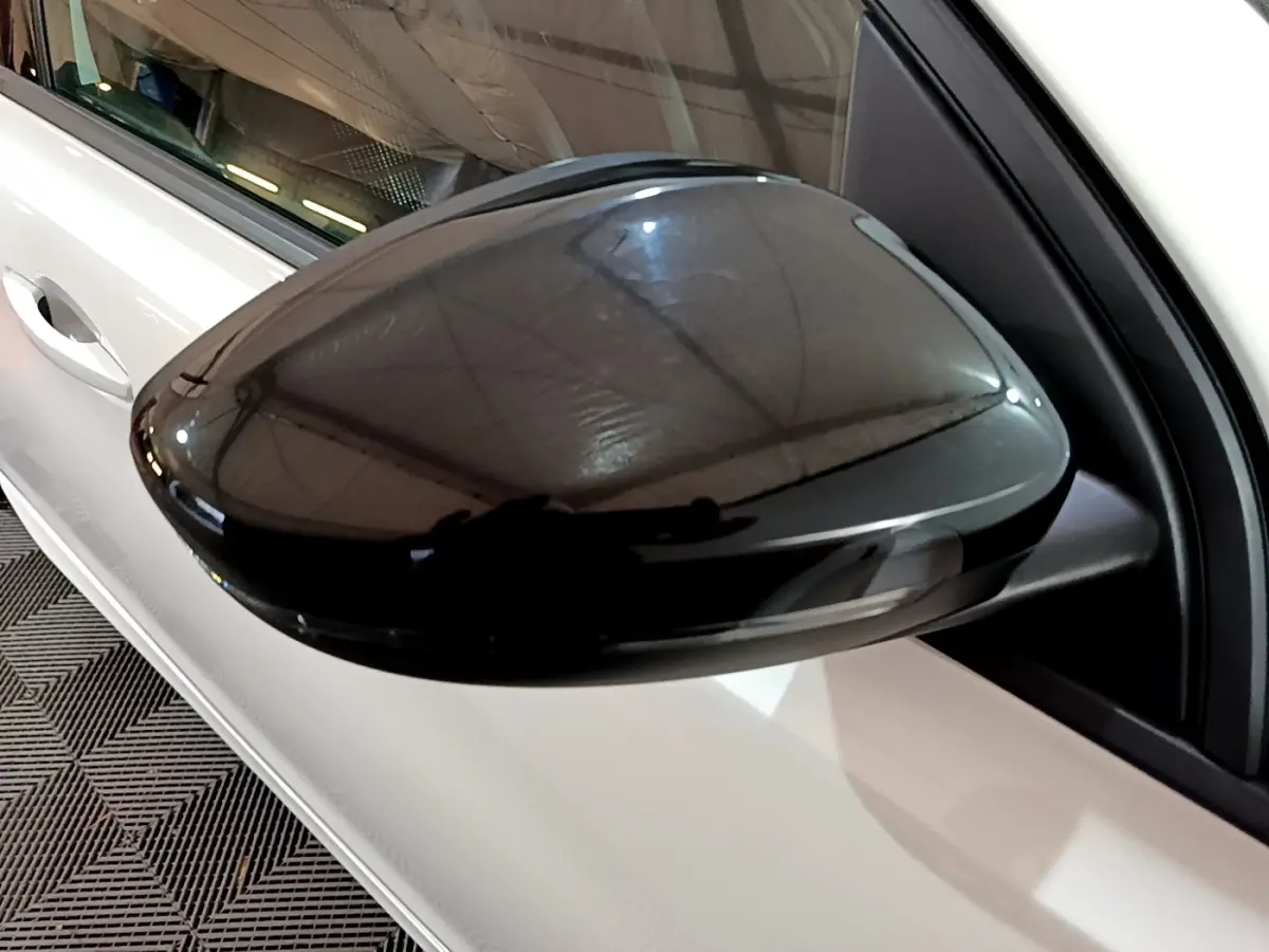 Rétroviseur noir côté gauche en gros plan sur Peugeot 308 blanc, version GT Line 2019, vue partielle latérale.