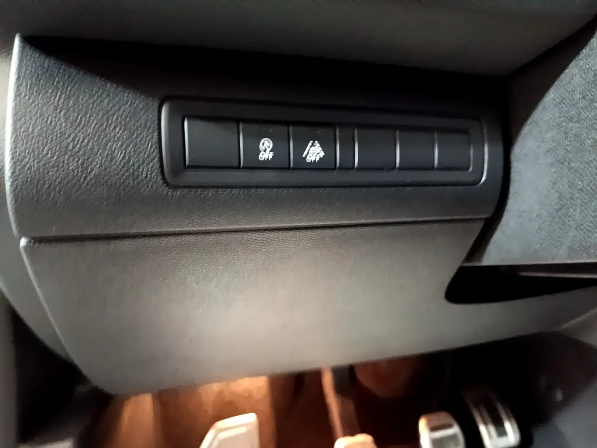 Gros plan sur les boutons de contrôle noirs sous le tableau de bord côté conducteur d'une Peugeot 308 blanche 2019.