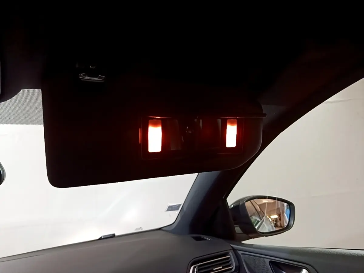 Détail intérieur du pare-soleil avec miroir éclairé côté droit sur Peugeot 308 blanc, vue depuis le siège conducteur.