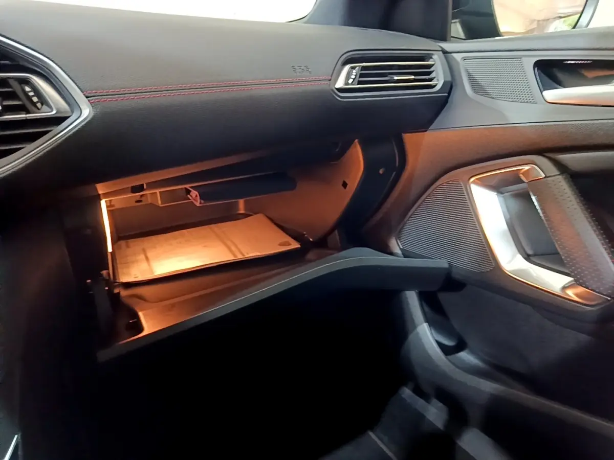 Intérieur de la Peugeot 308 GT Line 2019, vue côté passager sur boîte à gants ouverte avec éclairage intérieur.