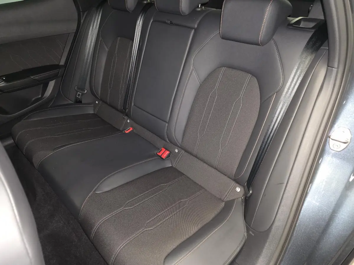 Vue intérieure de la banquette arrière bimatière noire du CUPRA Formentor gris, avec ceinture de sécurité et porte ouverte.