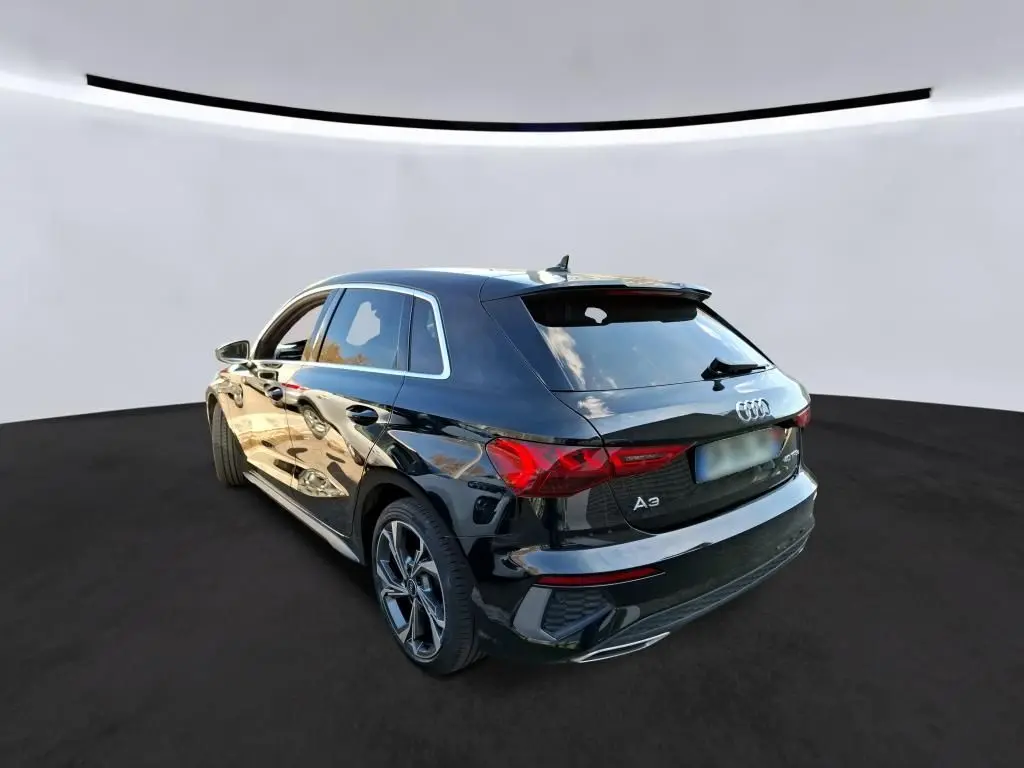Audi A3 Sportback noire vue 3/4 arrière droit, avec jantes alliage 18'' et vitres arrière surteintées.