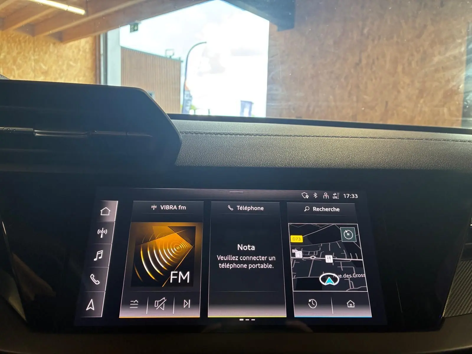 Écran central tactile de l’Audi A3 Sportback 2023 affichant radio FM, téléphone et navigation, vue intérieure frontale.