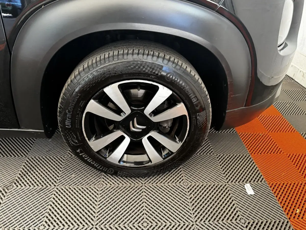 Gros plan sur la roue avant gauche noire d'une Citroën C3 Aircross 2020 avec jante alliage et logo Citroën central.