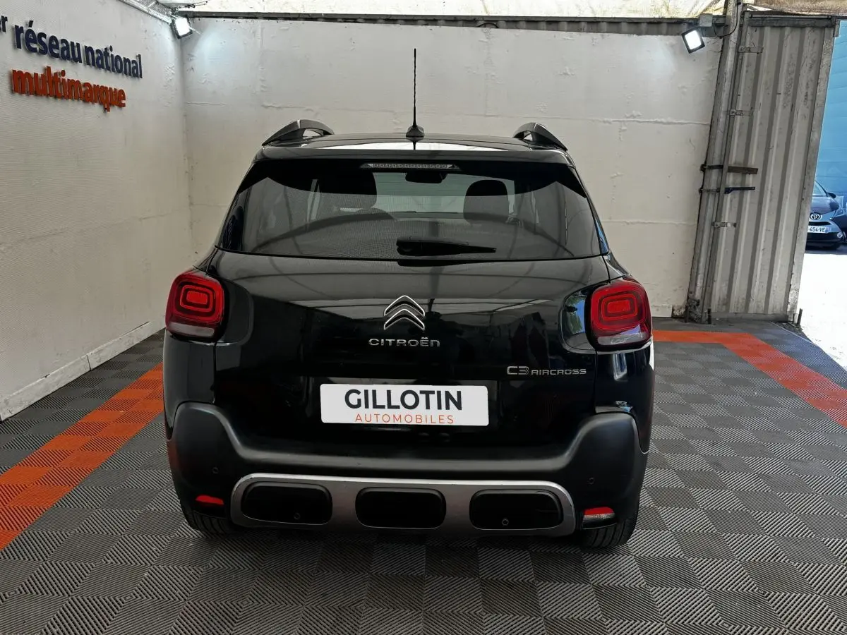 Vue arrière d'un Citroën C3 Aircross noir 2020 avec feux arrière carrés et pare-chocs noir mat, en intérieur showroom.