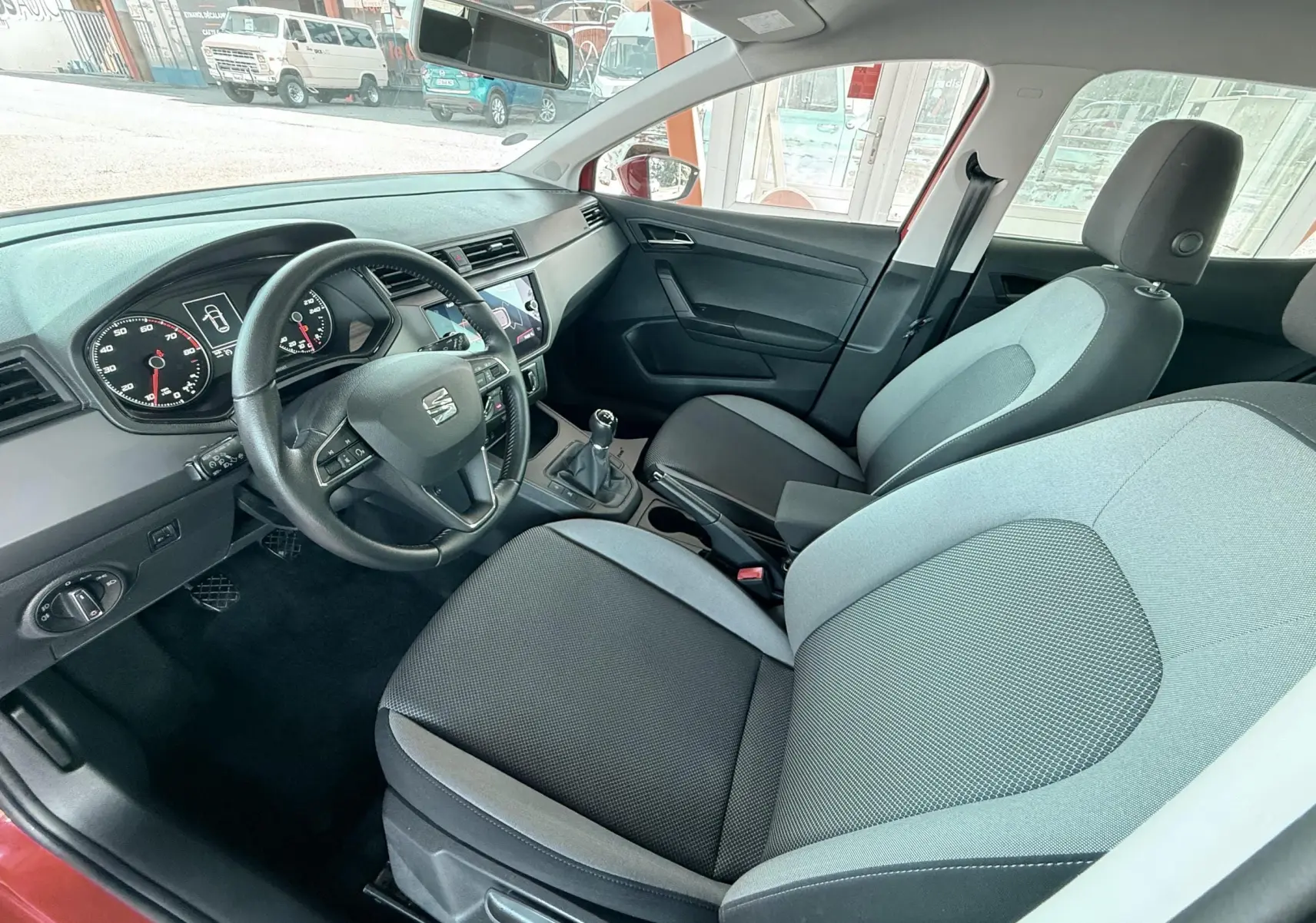 Vue intérieure côté conducteur de la SEAT Ibiza 2020, montrant sièges tissu gris noir et volant cuir multifonction.