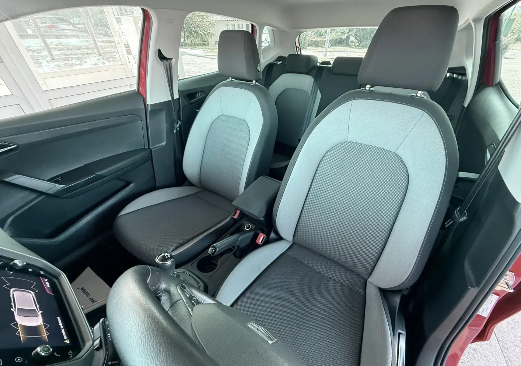 Vue intérieure avant droite de la SEAT Ibiza rouge passion, sièges tissu gris clair et foncé avec volant cuir noir.
