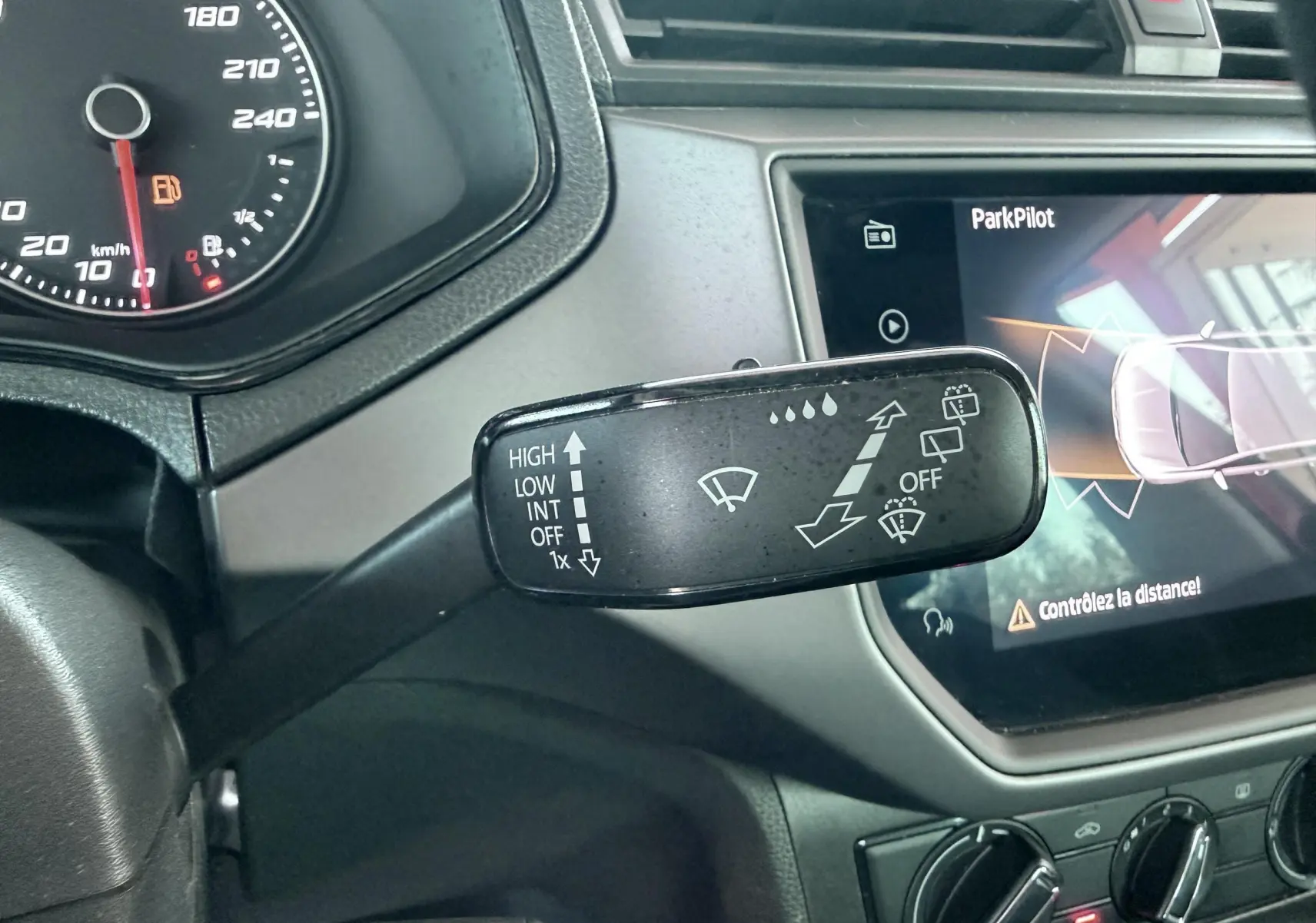 Gros plan sur la commande d’essuie-glace à gauche du volant dans l’habitacle gris noir d’une SEAT Ibiza rouge.
