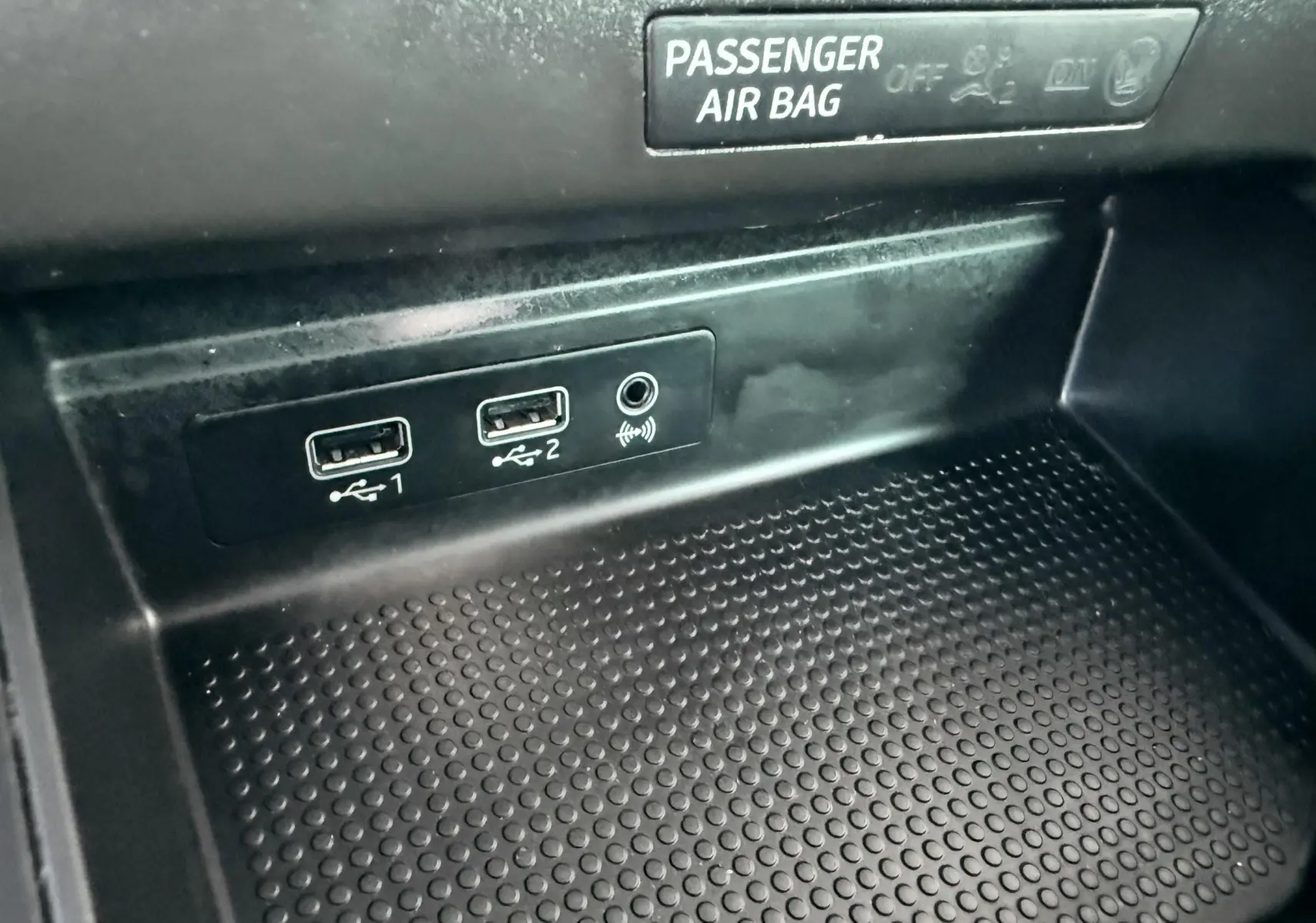 Gros plan sur la console centrale de la SEAT Ibiza rouge, montrant deux ports USB et une prise jack sous l'indicateur airbag passager.