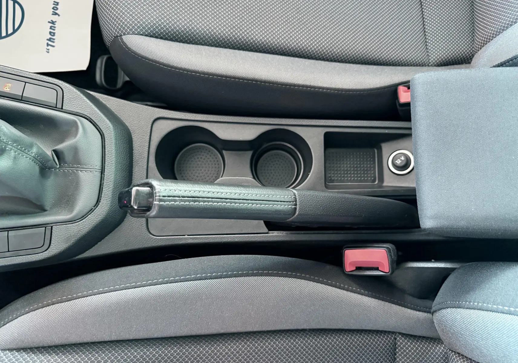 Vue plongeante sur la console centrale d'une SEAT Ibiza 2020, montrant frein à main, porte-gobelets et sièges gris.