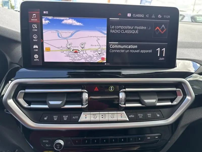 Vue rapprochée de l’écran tactile et de la console centrale du BMW X3 xDrive30e 2023 avec navigation et commandes climatisation.