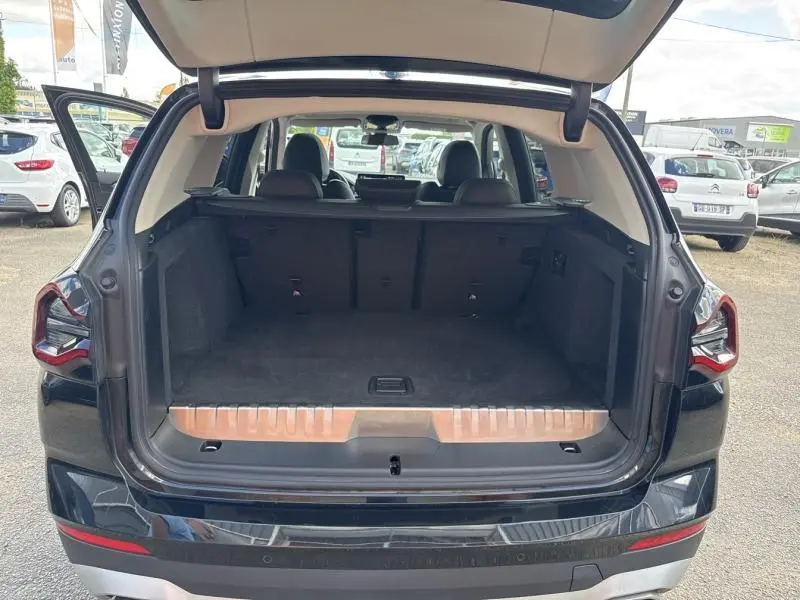Vue arrière du coffre ouvert d'un BMW X3 xDrive30e 2023 en Saphirschwarz métallisé, montrant l'espace de chargement vide.