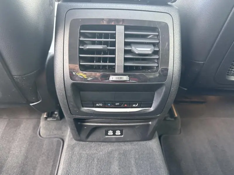 Vue rapprochée des commandes de climatisation arrière et prises USB dans l'habitacle noir du BMW X3 xDrive30e 2023.