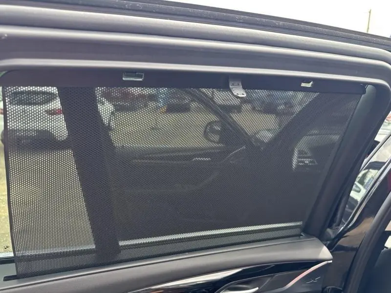 Store pare-soleil déployé sur la vitre arrière côté droit d’un BMW X3 Saphirschwarz métallisé 2023.
