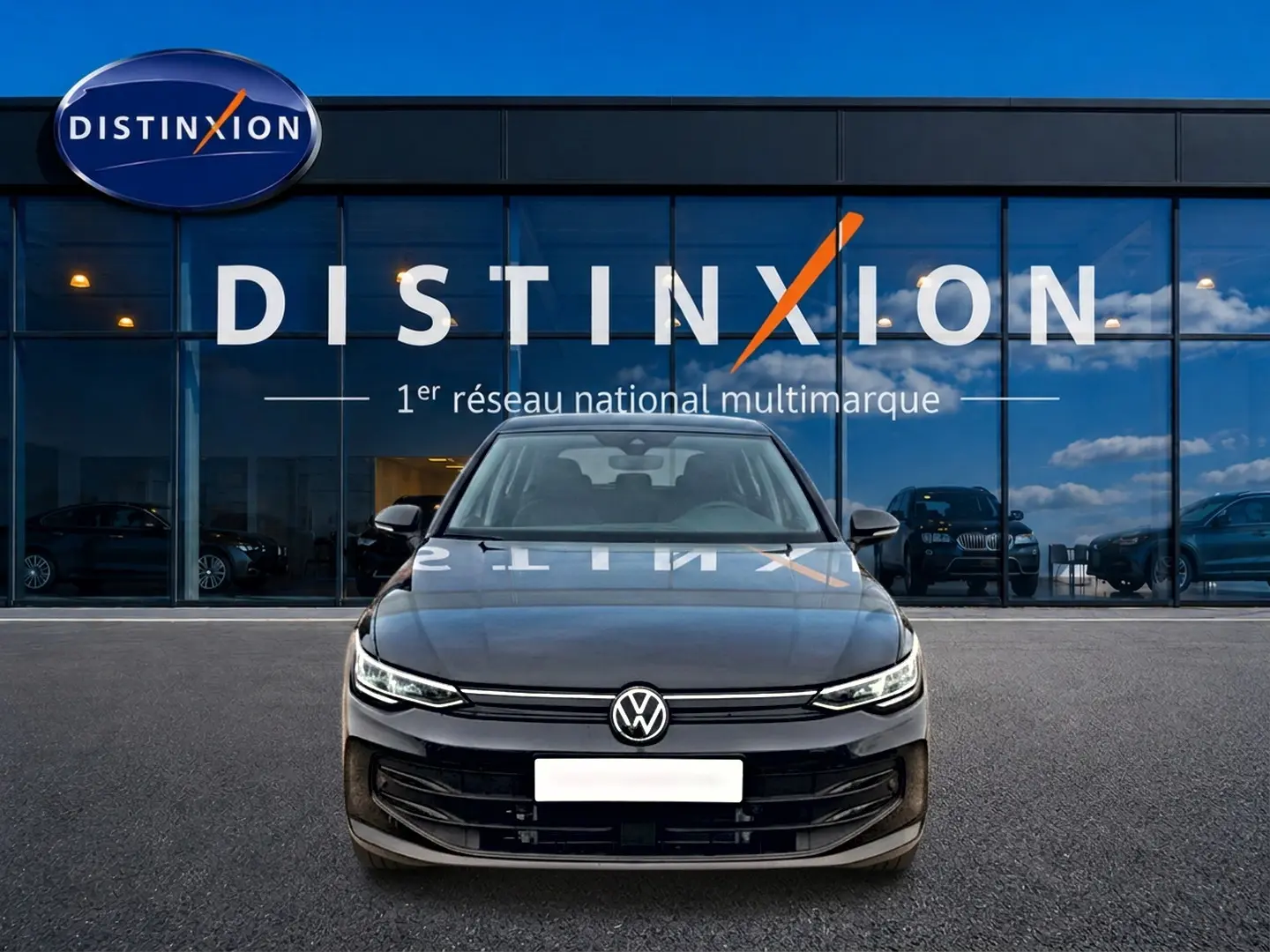 Vue frontale d'une Volkswagen Golf noire 2026 garée devant une vitrine avec logo Distinxion en arrière-plan.