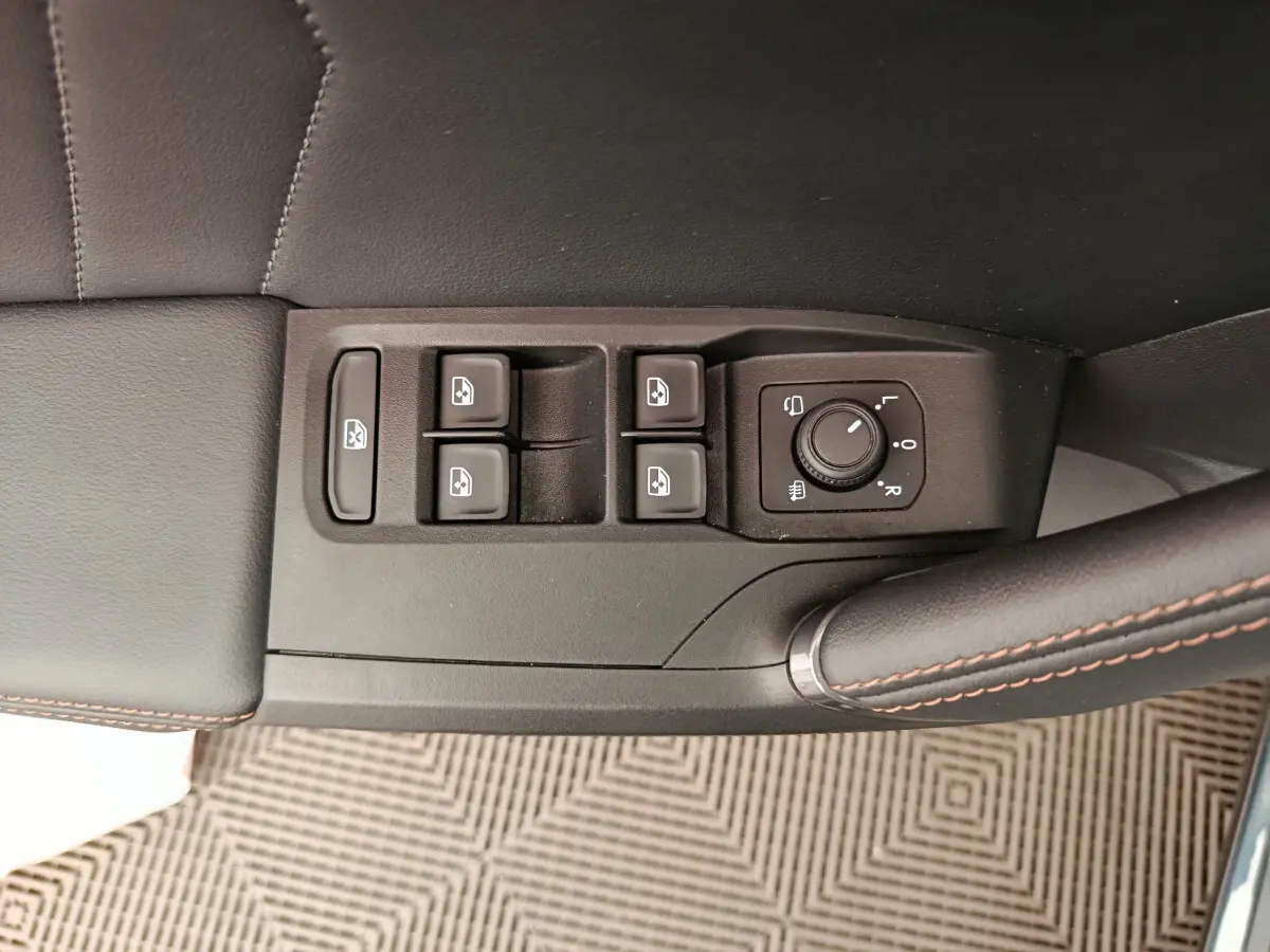 Gros plan sur les commandes de lève-vitres et réglage des rétroviseurs côté conducteur du CUPRA LEON ST gris foncé 2024.