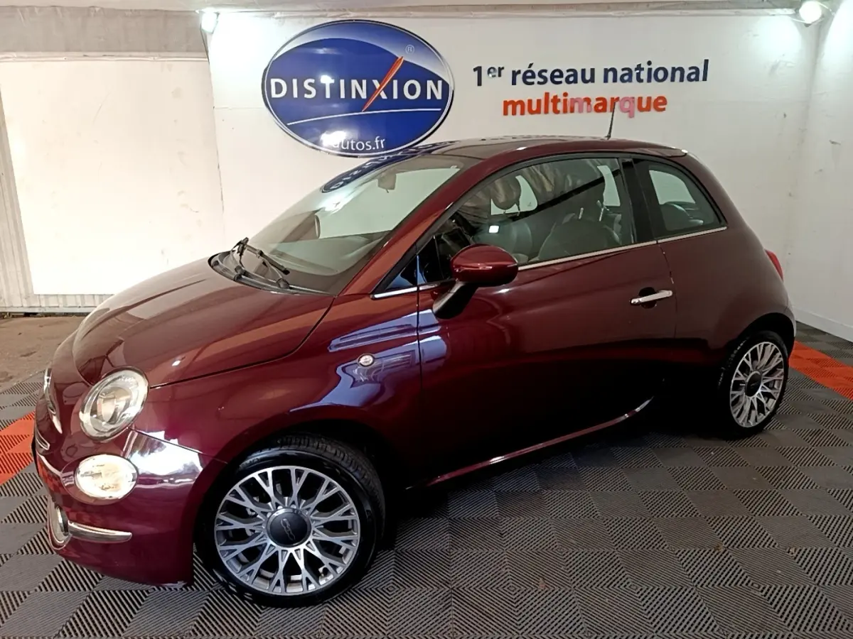 Profil droit d'une FIAT 500 rouge bordeaux 2021 avec jantes alliage et rétroviseurs assortis en intérieur showroom.