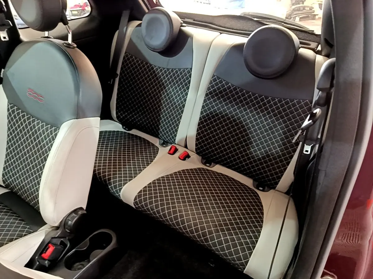 Vue intérieure côté droit des sièges arrière et avant en tissu noir à motifs blancs de la FIAT 500 rouge de 2021.