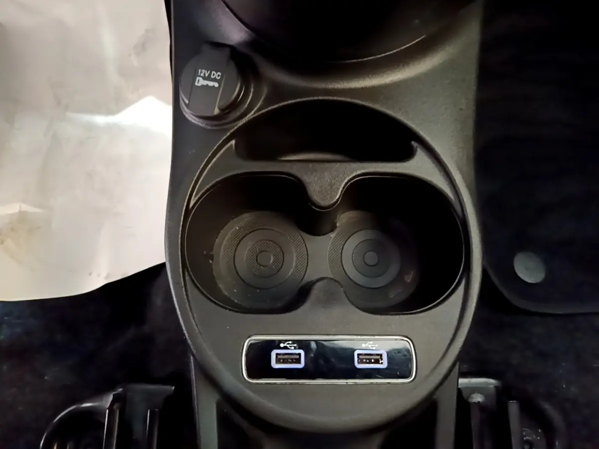 Vue rapprochée de la console centrale noire avec porte-gobelets et deux ports USB de la Fiat 500 rouge 2021.