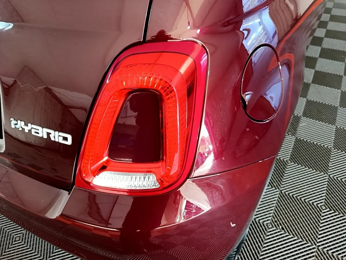 Gros plan sur le feu arrière droit rouge et l'inscription Hybrid d'une FIAT 500 rouge brillante.
