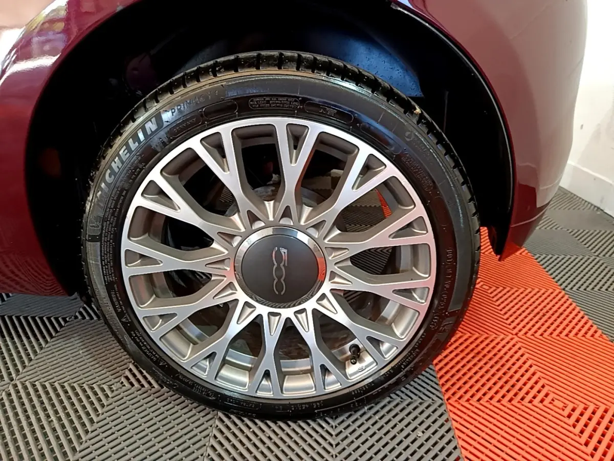Gros plan sur la roue avant droite de la FIAT 500 rouge 2021 avec jante alliage argentée à motifs fins.