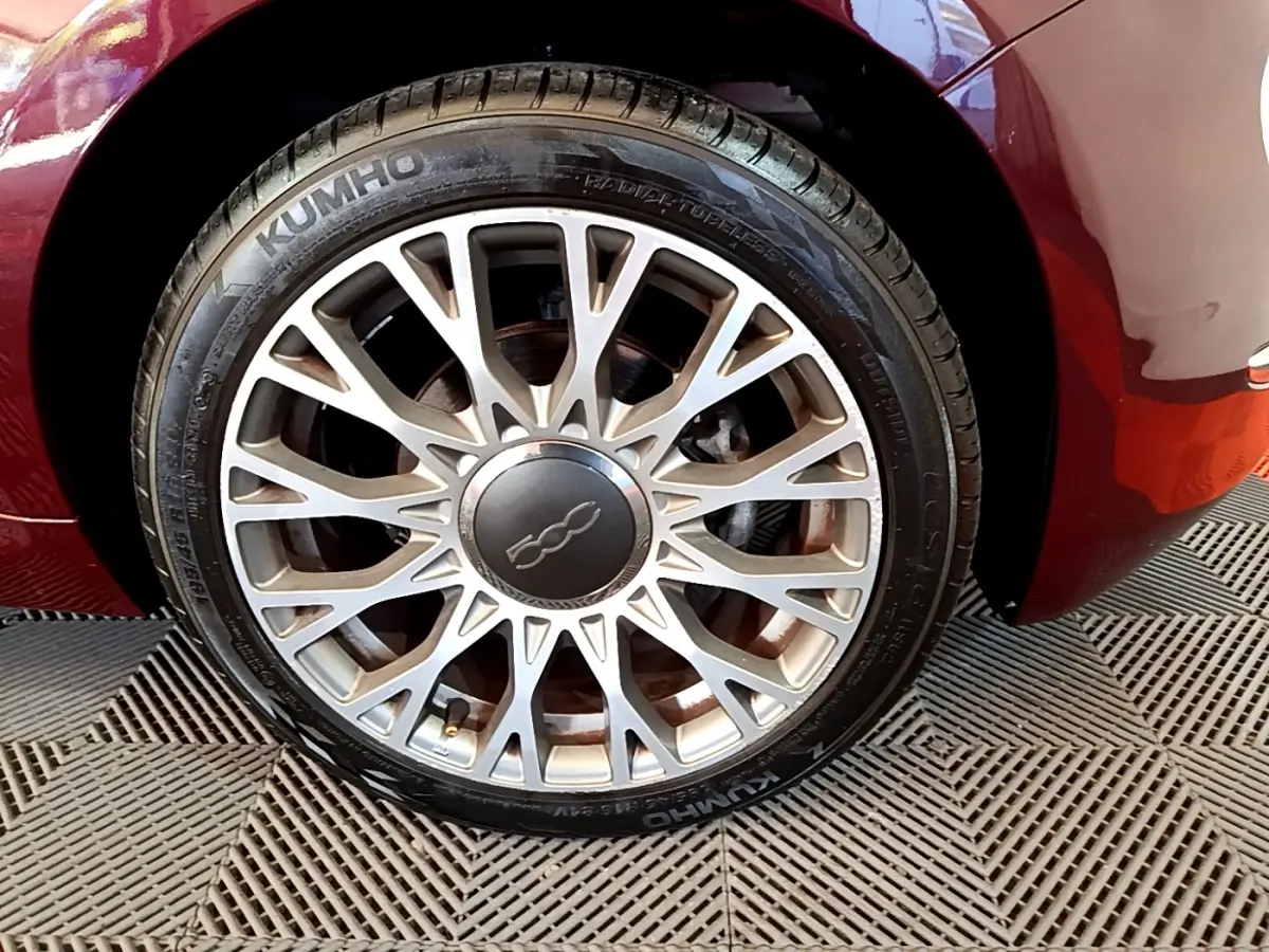 Gros plan sur la roue avant gauche rouge de la FIAT 500 avec jante alliage multi-branches argentée.