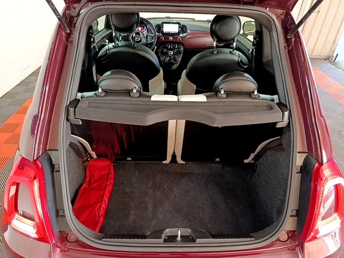 Vue arrière du coffre ouvert d'une FIAT 500 rouge 2021, montrant l'intérieur et les sièges noirs avec détails clairs.