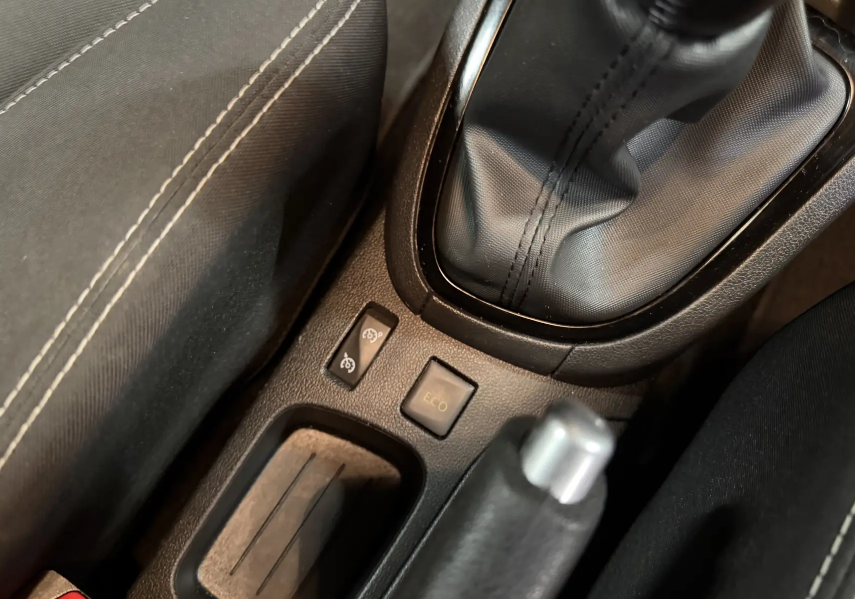 Gros plan sur la console centrale noire de la Renault Clio Estate IV rouge, montrant levier de vitesse manuel et bouton Eco.