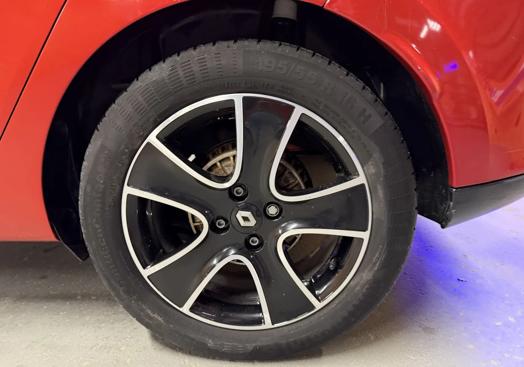 Gros plan sur la roue arrière droite d'une Renault Clio Estate IV rouge avec jante alliage noire et argentée.