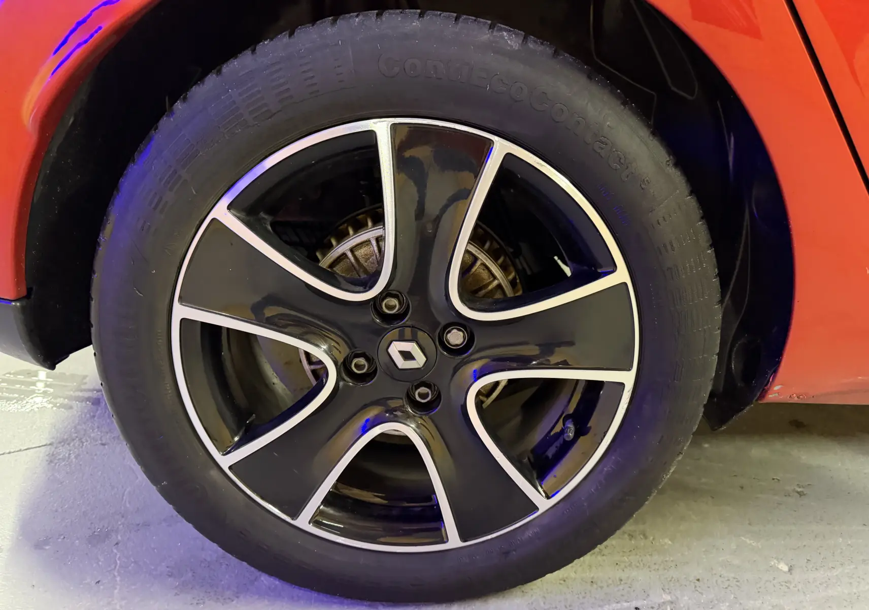 Gros plan sur la roue avant gauche de la Renault Clio Estate IV rouge, avec jante noire et argentée au design moderne.