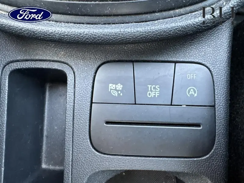 Gros plan sur les boutons de commande noirs du tableau de bord de la Ford Fiesta blanche, avec fonction arrêt auto du moteur.