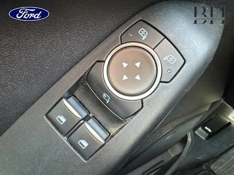 Gros plan sur les commandes de réglage des rétroviseurs et des vitres côté conducteur d'une Ford Fiesta blanc glacier 2020.