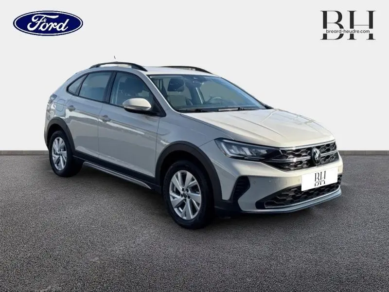 Volkswagen Taigo blanc pur en 3/4 avant droit, avec barres de toit et jantes alu visibles.