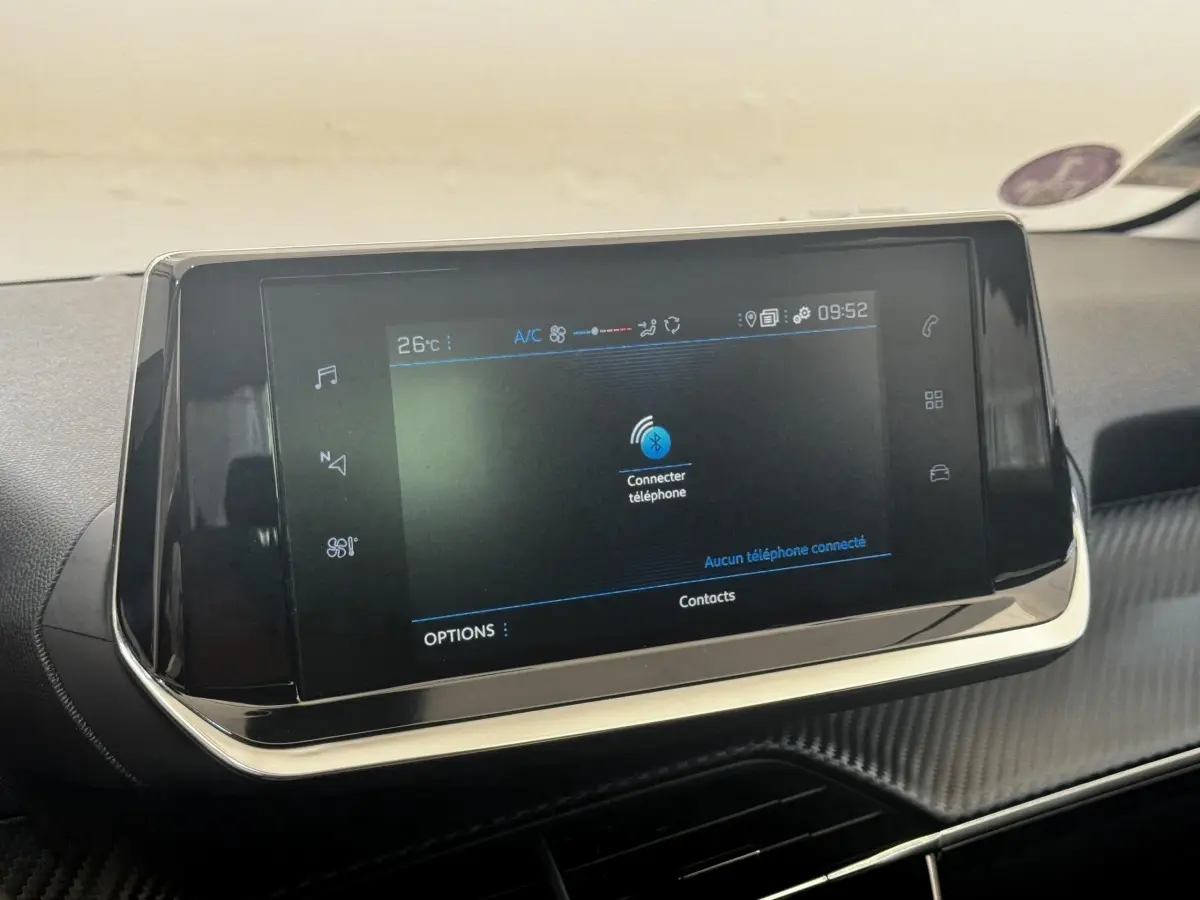Écran tactile central noir affichant la connexion Bluetooth dans l’habitacle d’une Peugeot 208 blanche.